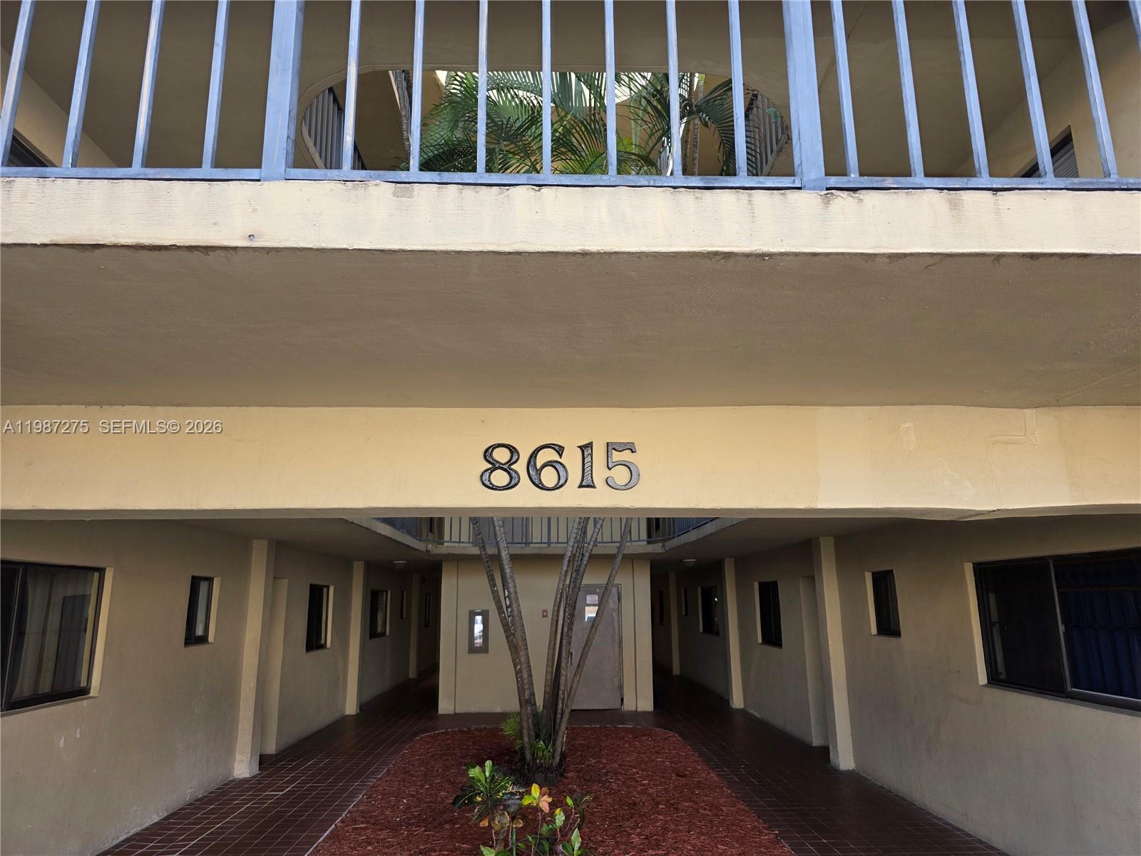 The exterior of a multi-story apartment building features a central walkway and address number 8615 — 8615 NW 8th St # 319, Miami FL 33126, MIAMI, FL