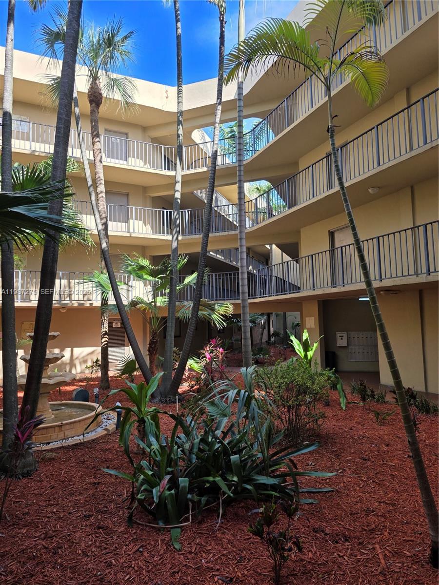 An open-air courtyard features a tiered fountain, palm trees, and multi-level apartment balconies — 8615 NW 8th St # 319, Miami FL 33126, MIAMI, FL