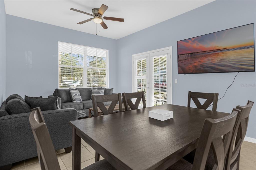 A dining area with a dark wood table and chairs sits adjacent to a living room — 4013 VENETIAN BAY DRIVE UNIT 107, KISSIMMEE, FL