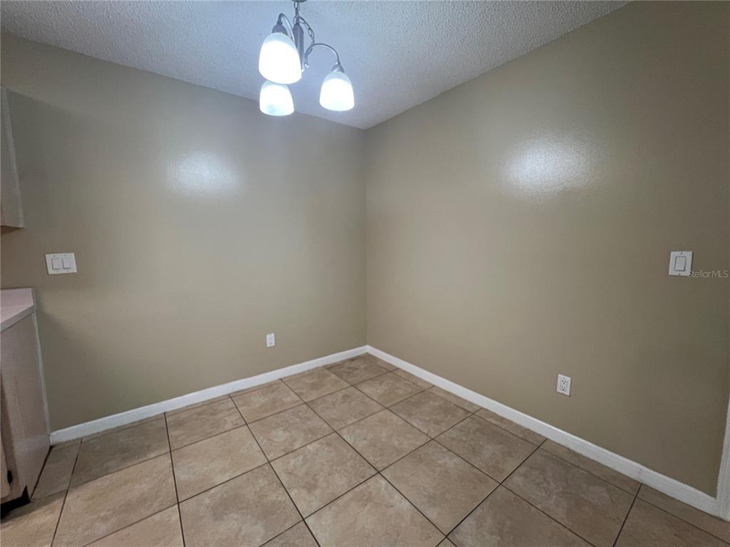 A small dining area features tan walls, a tile floor, and a three-light pendant fixture — 709 SECRET HARBOR LN UNIT 207, LAKE MARY, FL