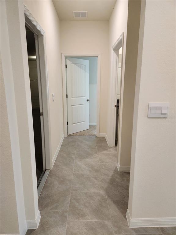 A hallway with light-colored walls, gray tile flooring, and three interior doors — 6930 AUDOBON OSPREY COVE, HARMONY, FL