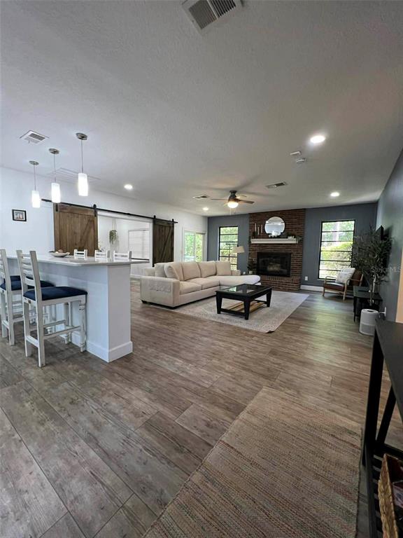 An open-concept living room features a kitchen island, sectional sofa, and a brick fireplace — 4455 NW 80TH TERRACE, OCALA, FL
