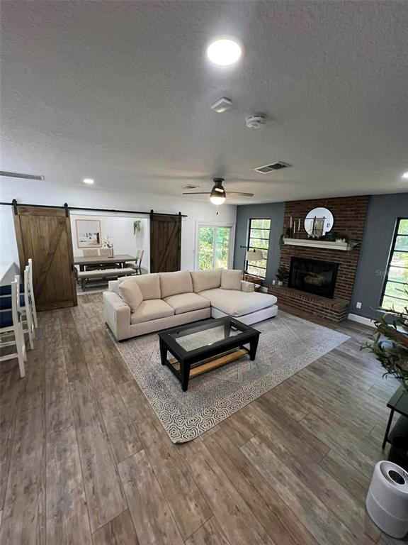 A living room features a sectional sofa, brick fireplace, and sliding barn doors to a dining area — 4455 NW 80TH TERRACE, OCALA, FL