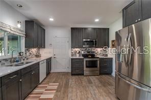 A kitchen features dark wood cabinets, stainless steel appliances, and light-colored countertops — 4455 NW 80TH TERRACE, OCALA, FL