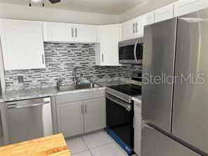 A kitchen features stainless steel appliances, white upper cabinets, gray lower cabinets, and a tiled backsplash — 44 S EDGEMON AVENUE, WINTER SPRINGS, FL