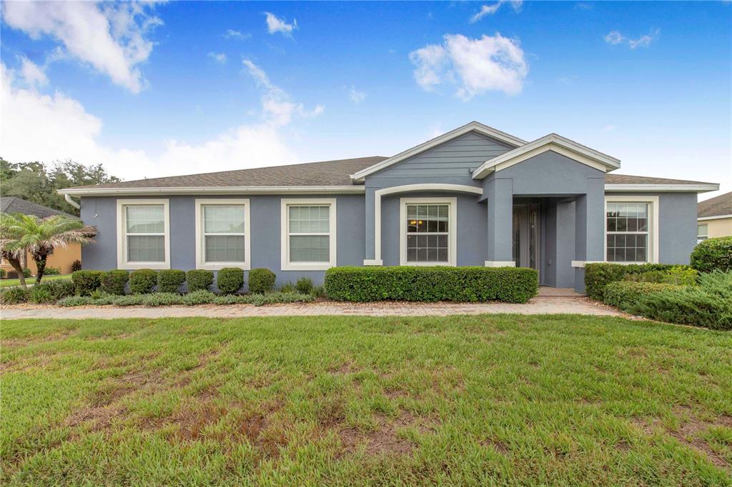 A single-story blue house with a paved walkway and manicured hedges in the front yard — 1020 LENA RUN COURT, WINTER HAVEN, FL