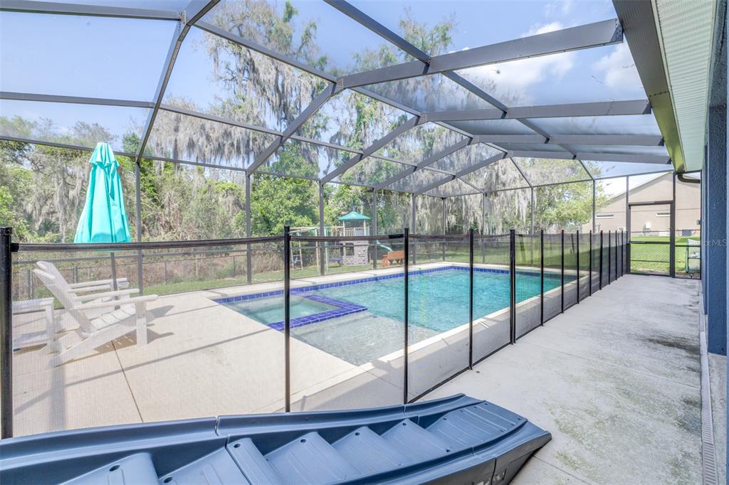 A screened-in patio features a swimming pool with a spa and a safety fence — 1020 LENA RUN COURT, WINTER HAVEN, FL