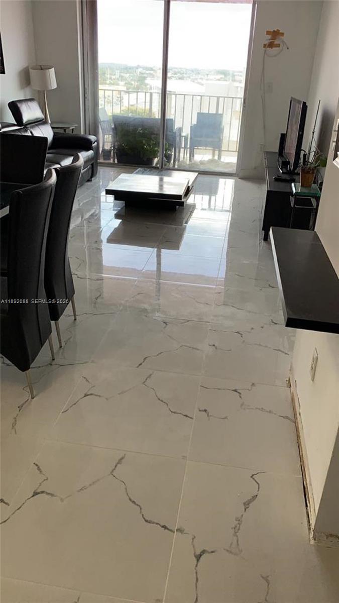 A living and dining area features white marble-look tile flooring and a sliding glass door — 4675 W 18th Ct # 1011, Hialeah FL 33012, HIALEAH, FL