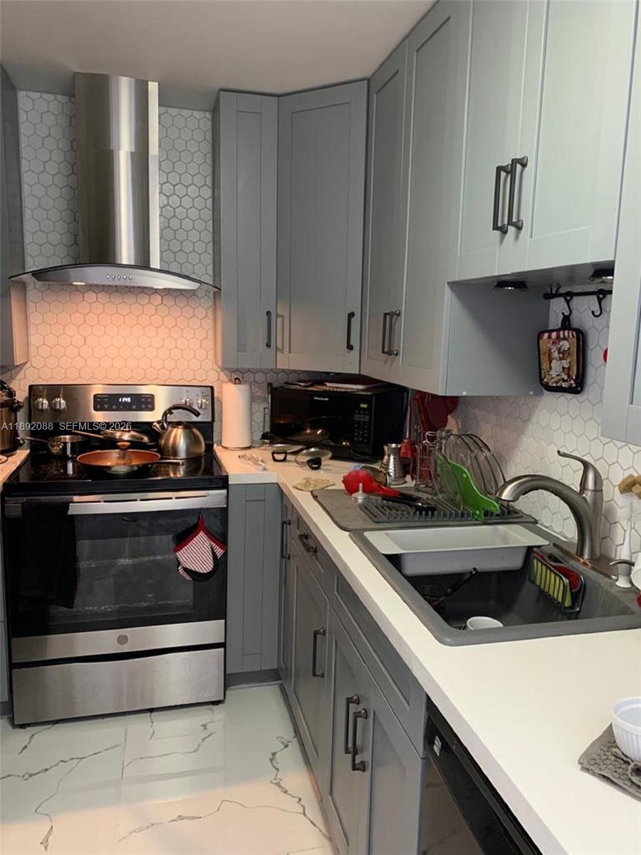 A kitchen features gray cabinets, white countertops, stainless steel appliances, and a hexagonal tile backsplash — 4675 W 18th Ct # 1011, Hialeah FL 33012, HIALEAH, FL