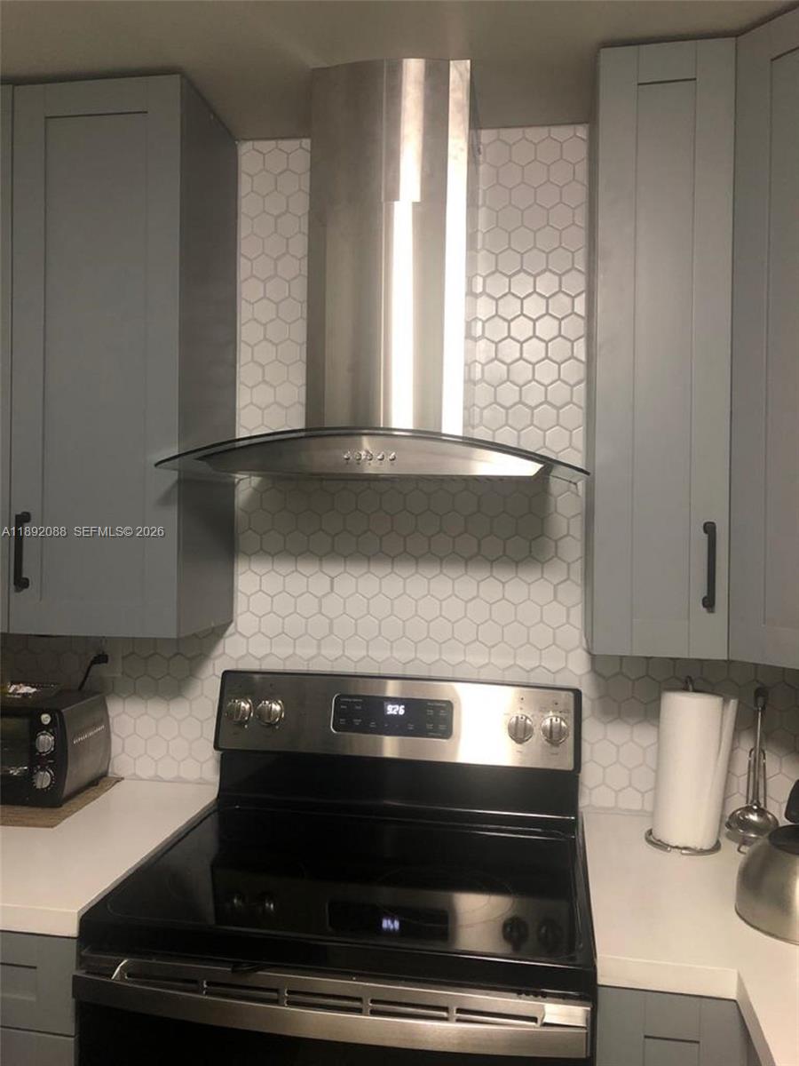 A kitchen features a stainless steel range hood, hexagonal tile backsplash, and gray cabinets — 4675 W 18th Ct # 1011, Hialeah FL 33012, HIALEAH, FL
