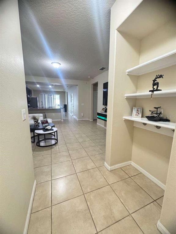 A tiled hallway leads toward a living area with a kitchen in the background — 2515 NOUVEAU WAY, KISSIMMEE, FL