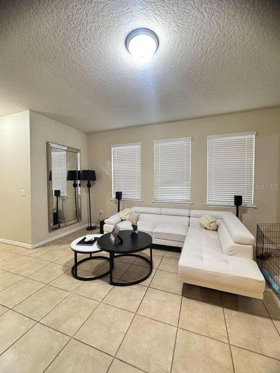 A living room features a white sectional sofa, two round coffee tables, and a large mirror — 2515 NOUVEAU WAY, KISSIMMEE, FL