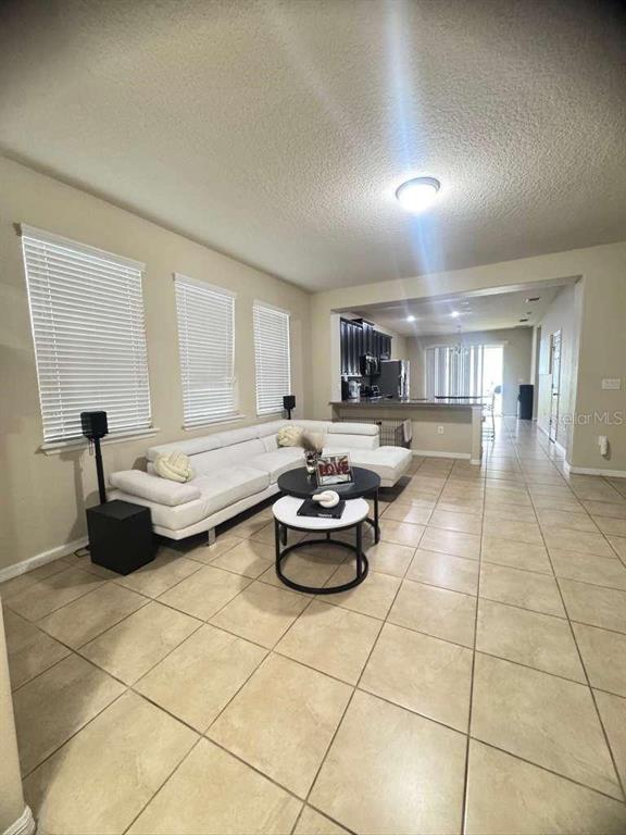 A living room with tile floors, a white sectional sofa, and an open kitchen — 2515 NOUVEAU WAY, KISSIMMEE, FL