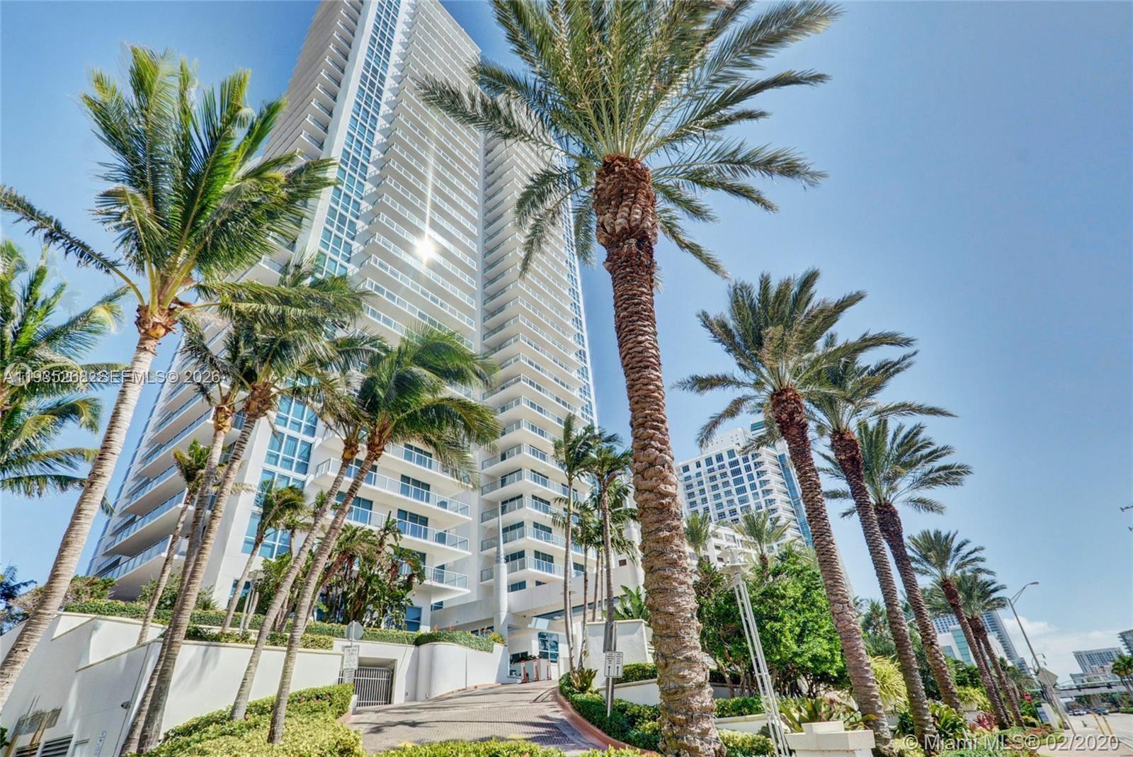 A tall white residential high-rise building is surrounded by palm trees on a sunny day — 3101 S Ocean Dr # 606, Hollywood FL 33019, HOLLYWOOD, FL