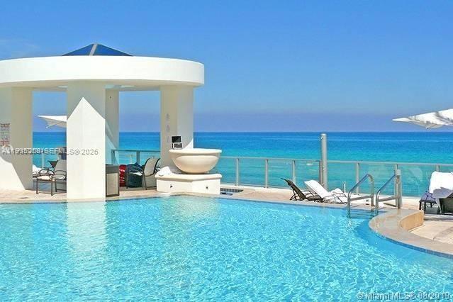 A swimming pool overlooks the ocean next to a white pavilion with a large bowl — 3101 S Ocean Dr # 606, Hollywood FL 33019, HOLLYWOOD, FL