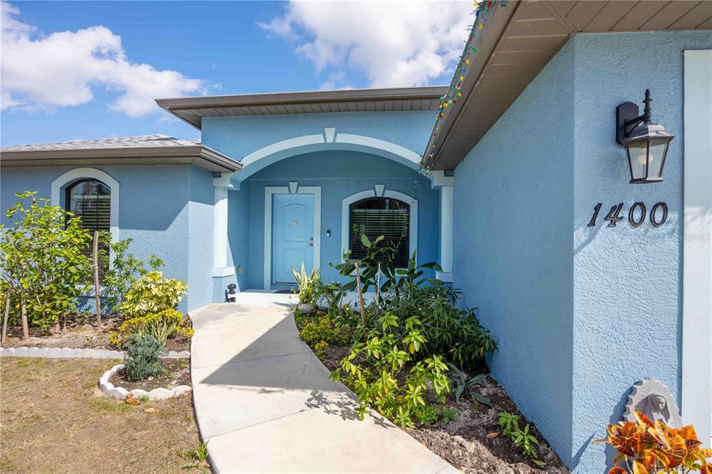 The exterior of a light blue house features a walkway leading to a covered entryway — 1400 NORDENDALE BOULEVARD, NORTH PORT, FL