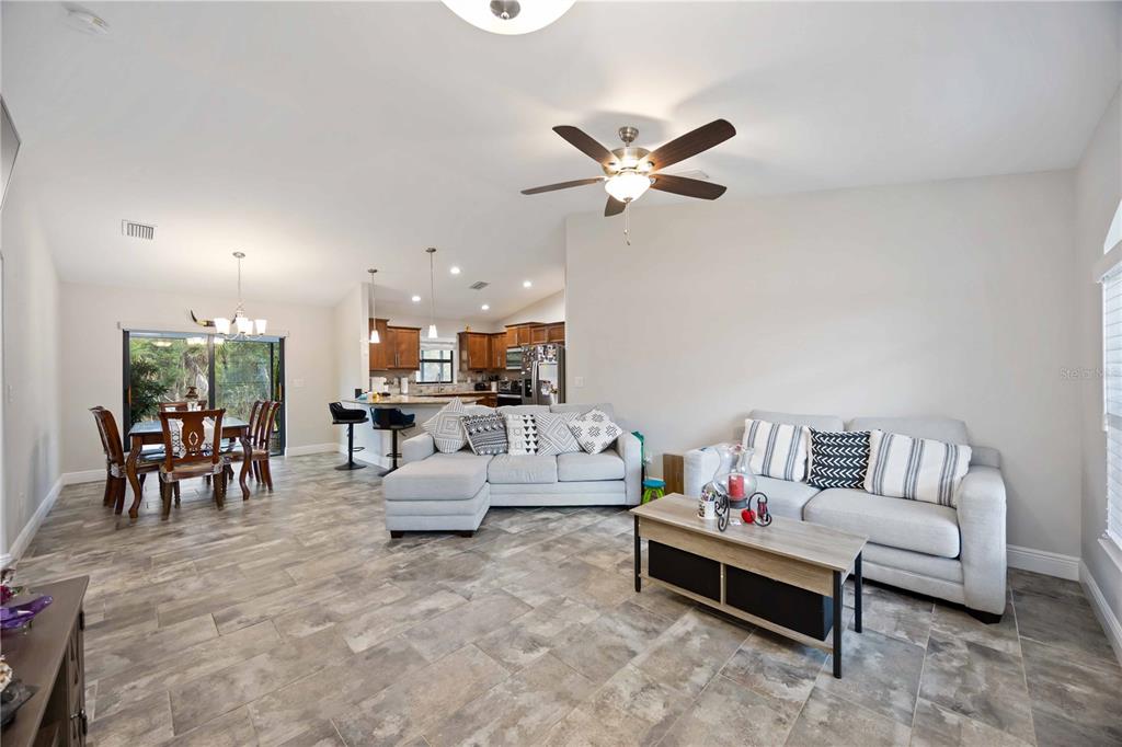 An open-concept living room and dining area features tile flooring, neutral walls, and a kitchen — 1400 NORDENDALE BOULEVARD, NORTH PORT, FL