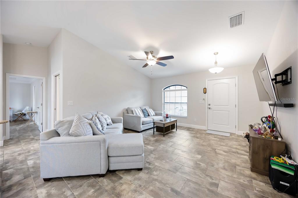 A living room with light gray tile floors, a sectional sofa, and a front door — 1400 NORDENDALE BOULEVARD, NORTH PORT, FL