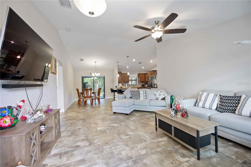An open-concept living room features tile flooring, a sectional sofa, and a dining area — 1400 NORDENDALE BOULEVARD, NORTH PORT, FL