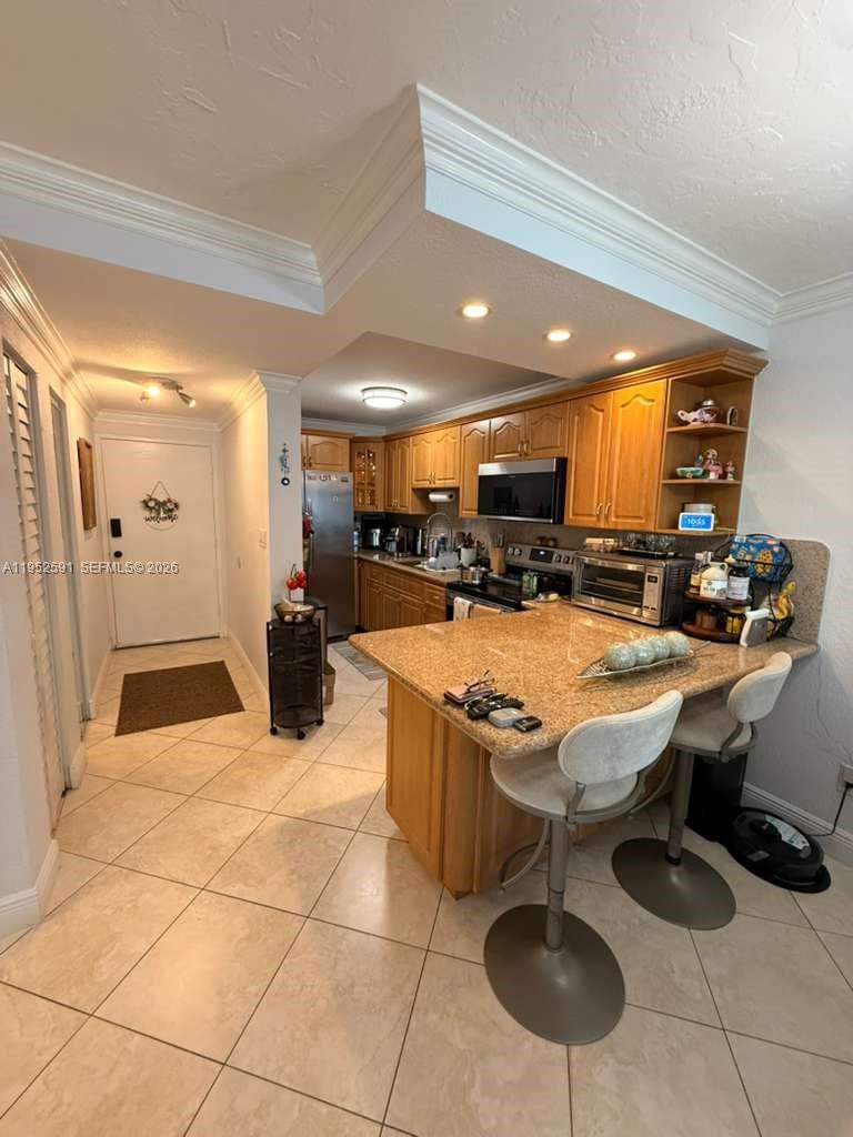 A kitchen features wood cabinets, granite countertops, a breakfast bar, and tile flooring — 5501 NW 7th St # E207, Miami FL 33126, MIAMI, FL