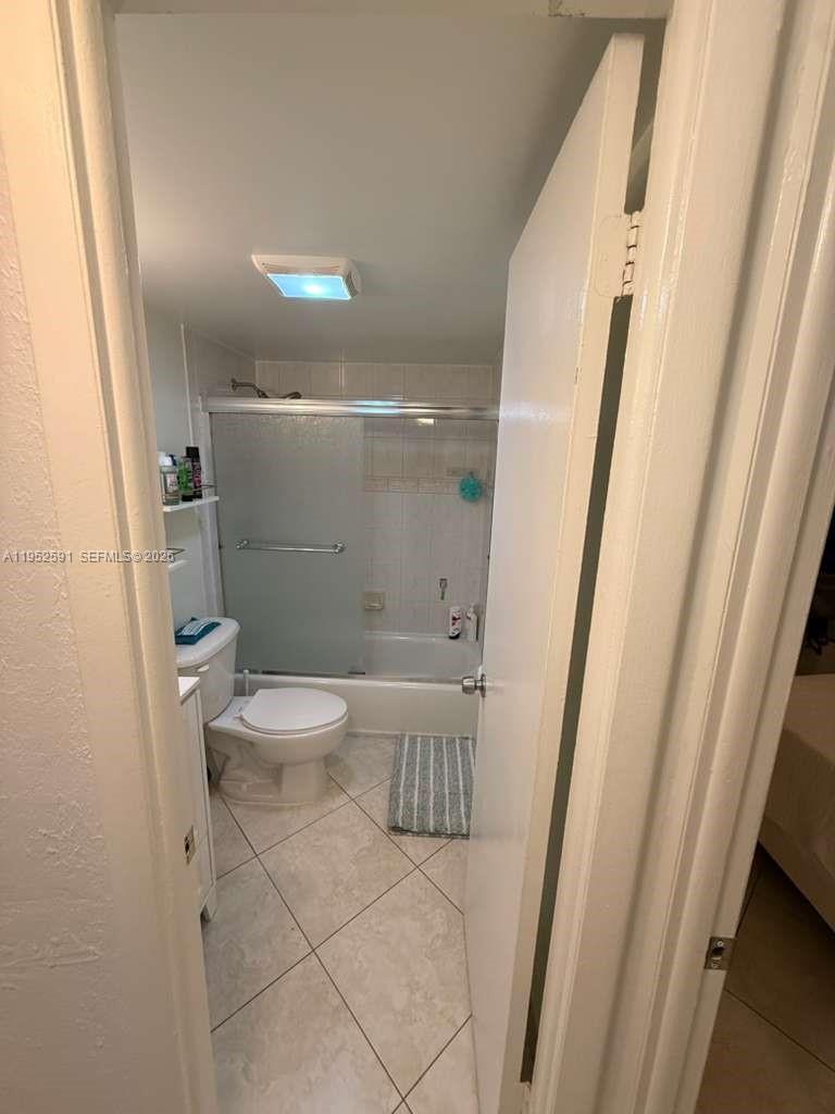 A small bathroom features a toilet, a vanity, and a shower-tub combination with sliding doors — 5501 NW 7th St # E207, Miami FL 33126, MIAMI, FL