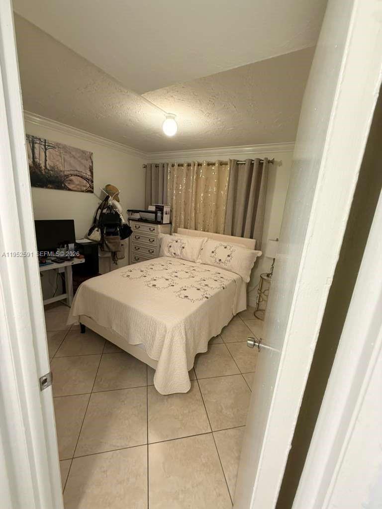 A bedroom features a bed with a white quilt, tiled floors, and a desk area — 5501 NW 7th St # E207, Miami FL 33126, MIAMI, FL