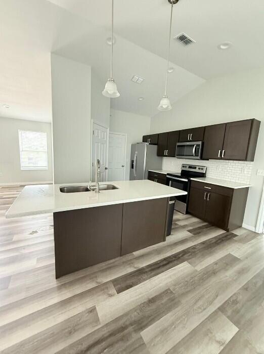 A modern kitchen features dark brown cabinets, a white island, and light wood-look flooring — 6823 SW 129th Street, Ocala FL 34473, OCALA, FL