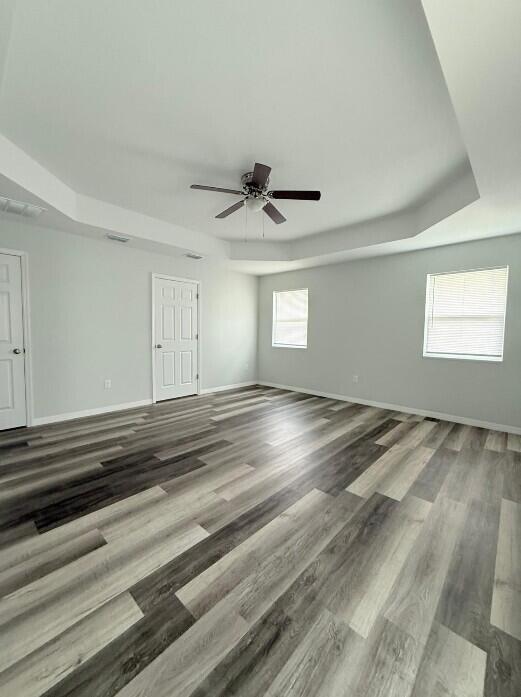 An empty bedroom features a tray ceiling, a ceiling fan, and light-colored wood-look flooring — 6823 SW 129th Street, Ocala FL 34473, OCALA, FL