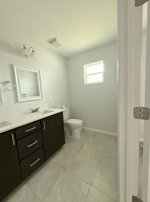 A bathroom features a dark wood vanity, a white countertop, a toilet, and tiled flooring — 6823 SW 129th Street, Ocala FL 34473, OCALA, FL