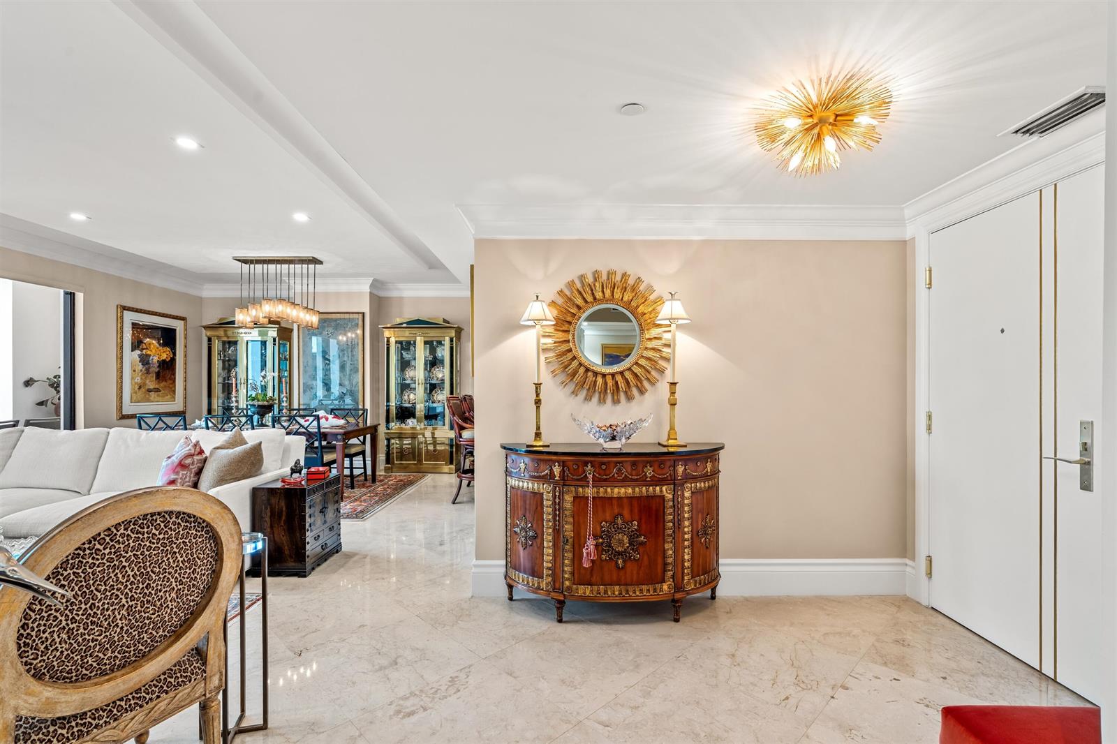 A foyer features a wood cabinet, sunburst mirror, and lamps, opening into a living room — 200 E Palmetto Park Road # 404, Boca Raton FL 33432, BOCA RATON, FL
