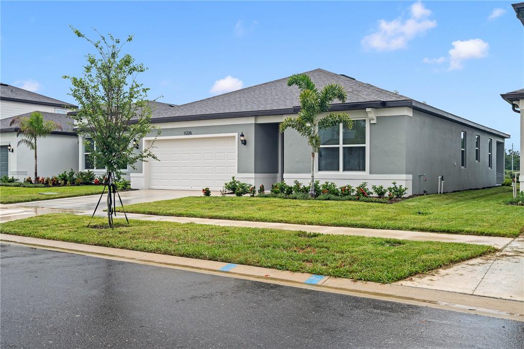 A single-story gray house with a two-car garage and a small front yard — 11226 SYCAMORE GLEN LOOP, THONOTOSASSA, FL