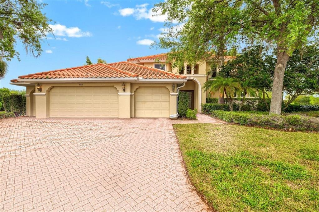 A two-story house with a terracotta tile roof and a paved driveway — 10115 DAY LILY COURT, BRADENTON, FL