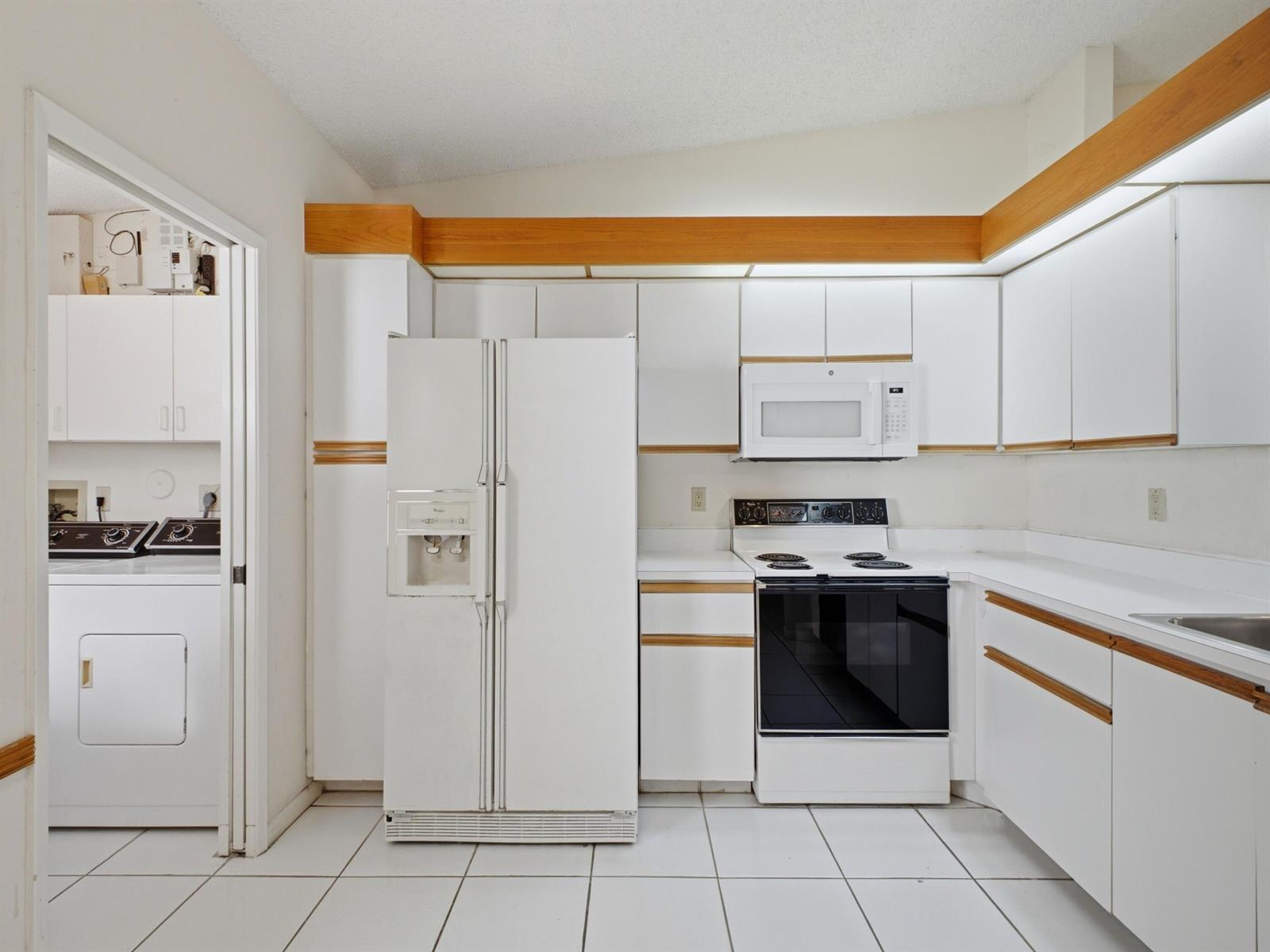 A kitchen with white cabinets, white appliances, and light-colored tile flooring — 6200 Kings Gate Circle, Delray Beach FL 33484, DELRAY BEACH, FL