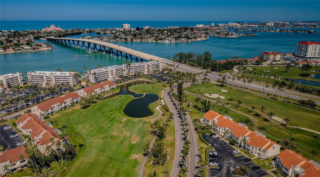 An aerial view shows a golf course, residential buildings, and a bridge over the water — 6191 BAHIA DEL MAR BOULEVARD UNIT 103, ST PETERSBURG, FL