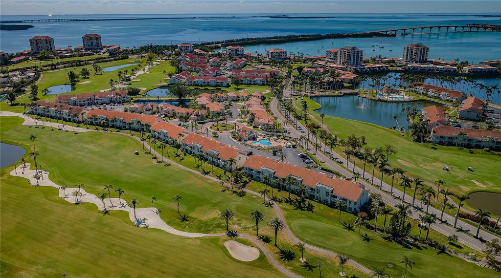 An aerial view shows a residential complex with red-roofed buildings situated on a golf course — 6191 BAHIA DEL MAR BOULEVARD UNIT 103, ST PETERSBURG, FL