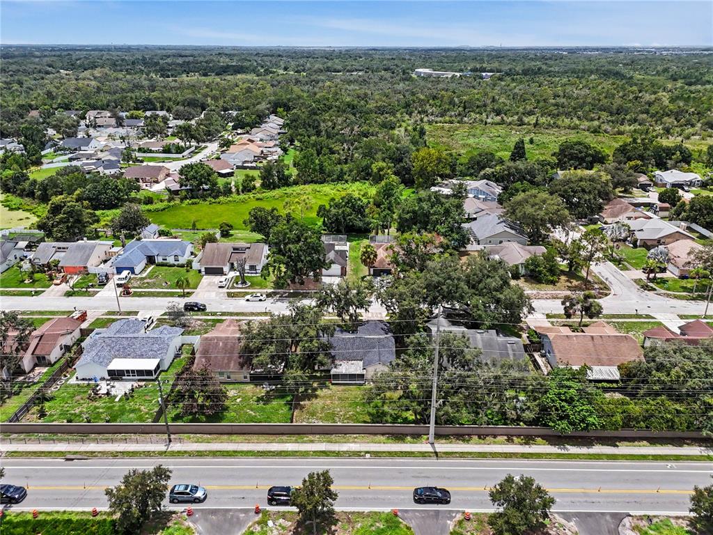 An aerial view shows a suburban neighborhood with houses, trees, and a multi-lane road — 12108 FRUITWOOD DRIVE, RIVERVIEW, FL