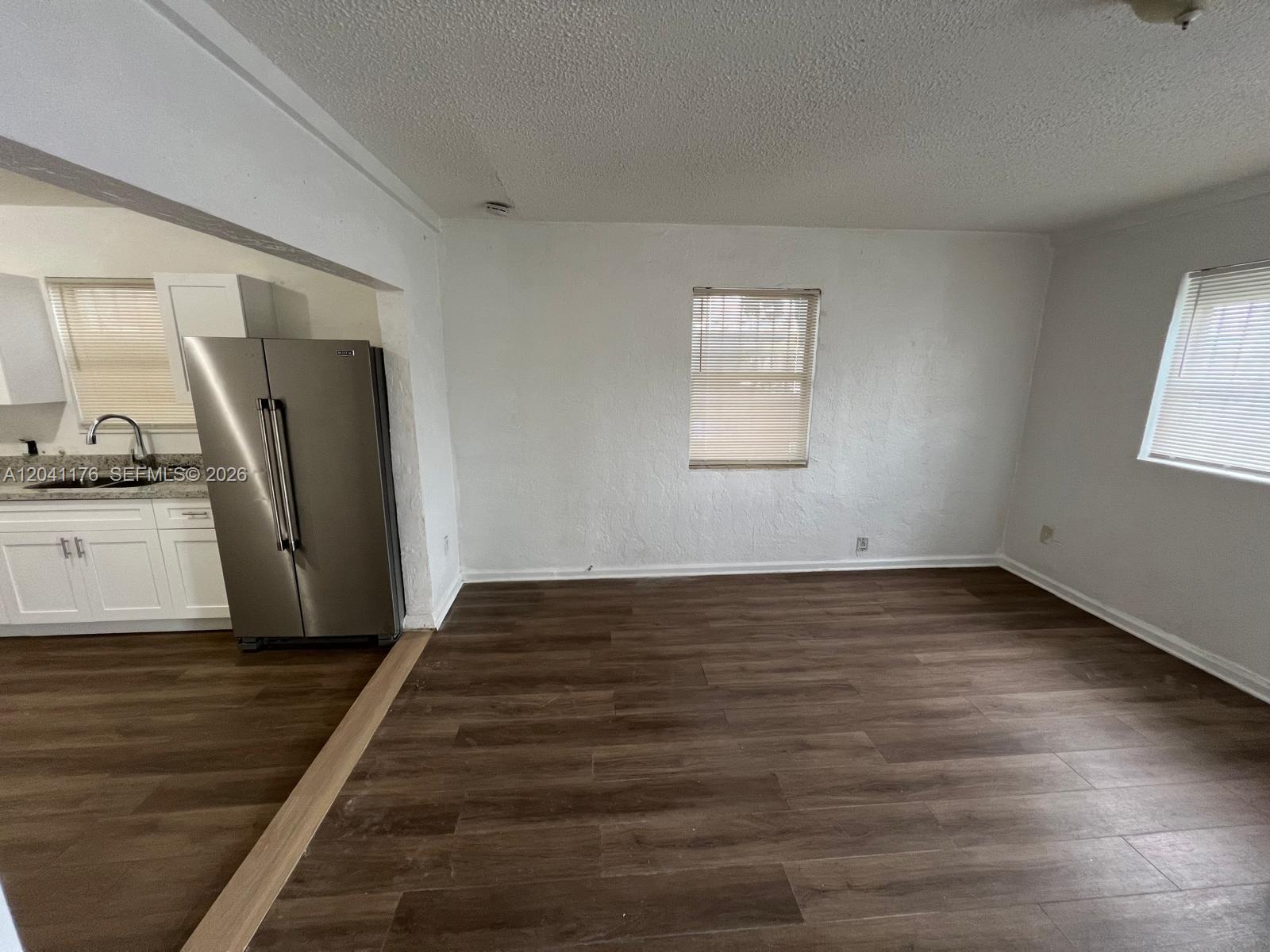 A kitchen with stainless steel appliances opens into a living area with wood-look flooring — 10 NW 71st St, Miami FL 33150, MIAMI, FL