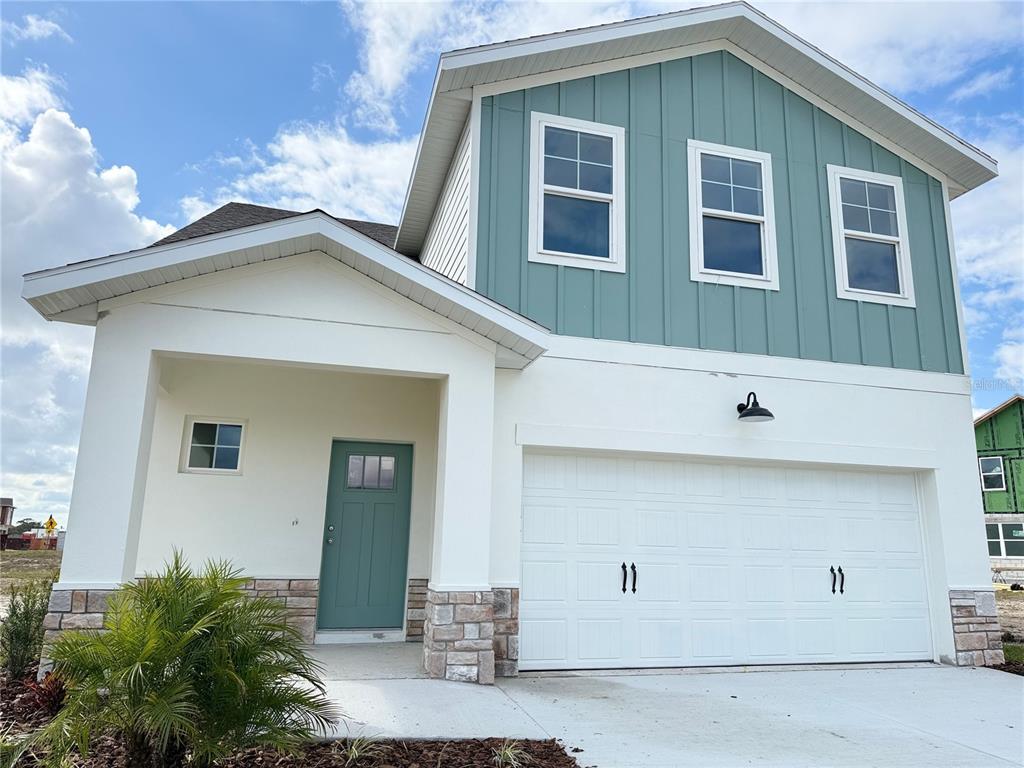 A two-story house with white stucco, teal vertical siding, a stone base, and a garage — 7978 CHANDLER LAKE COURT, HUDSON, FL