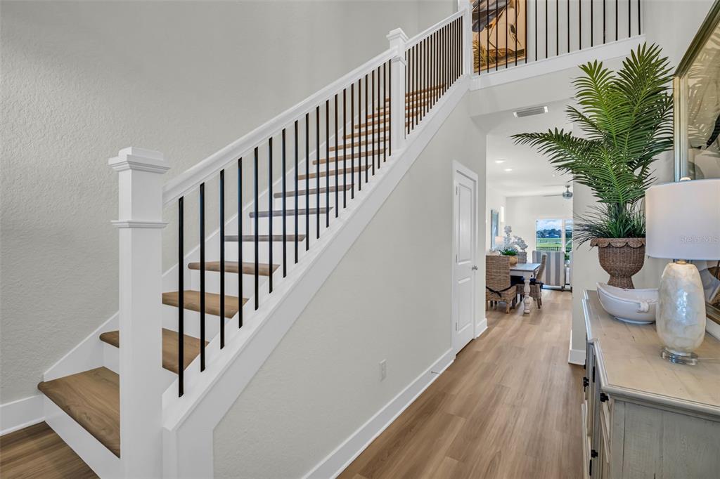 A staircase with black metal railings leads to an upper level in a bright entryway — 7978 CHANDLER LAKE COURT, HUDSON, FL