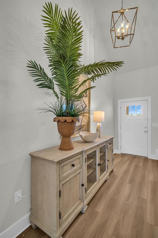 A light-wood console table with a large potted palm sits in a bright entryway — 7978 CHANDLER LAKE COURT, HUDSON, FL