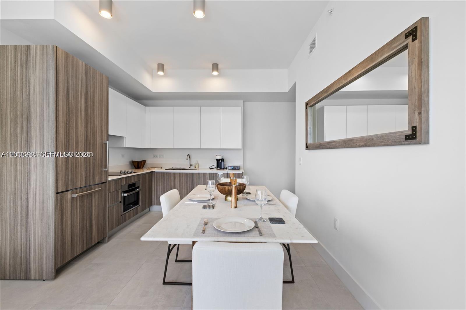 A modern kitchen and dining area feature white cabinets, wood-grain paneling, and a marble table — 239 SW 9th St # 1502, Miami FL 33130, MIAMI, FL