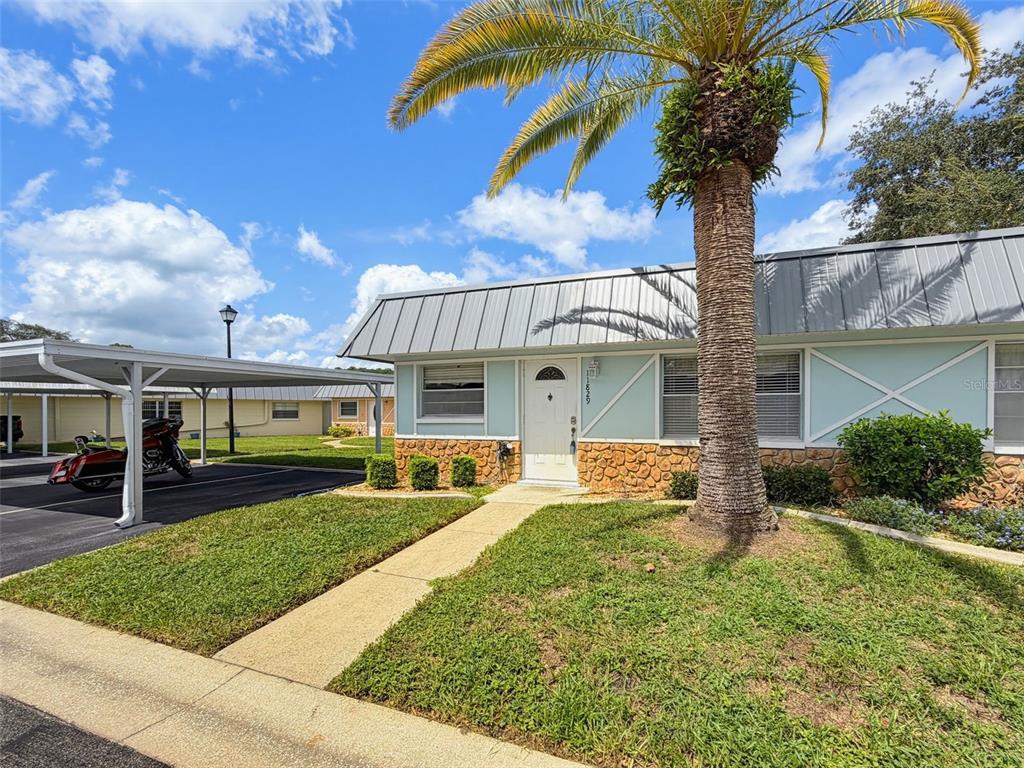 A single-story house with a metal roof, stone facade, and a palm tree in front — 11829 CARISSA LANE UNIT A, NEW PORT RICHEY, FL