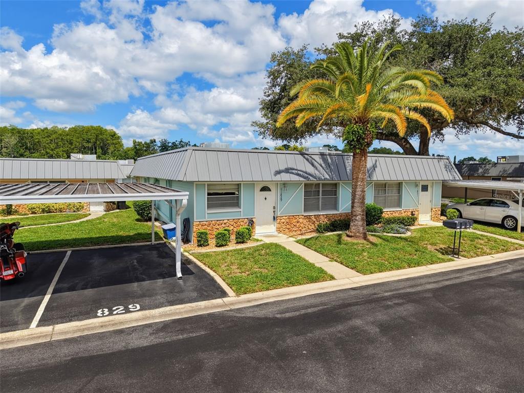 A single-story duplex with a metal roof, stone facade, and a covered carport — 11829 CARISSA LANE UNIT A, NEW PORT RICHEY, FL