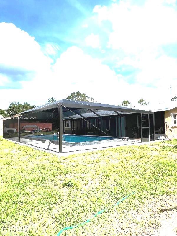 A screened-in swimming pool sits in the backyard of a single-story house — 826 B Rd., La Belle FL 33935, LA BELLE, FL