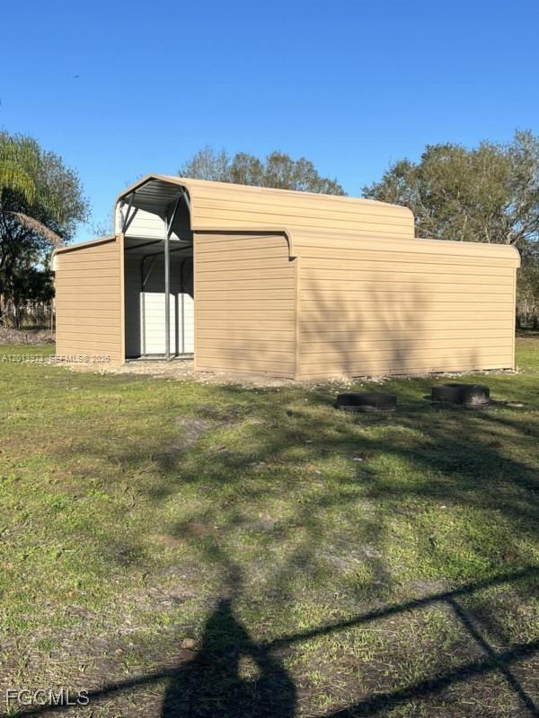A tan metal barn-style structure with an open center bay sits on a grassy lot — 826 B Rd., La Belle FL 33935, LA BELLE, FL