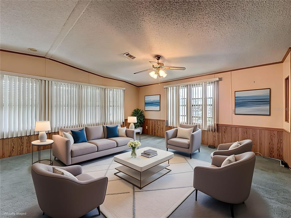 A living room features wood-paneled walls, a ceiling fan, and virtual staging furniture — 449 TIVOLI PARK DRIVE, DAVENPORT, FL