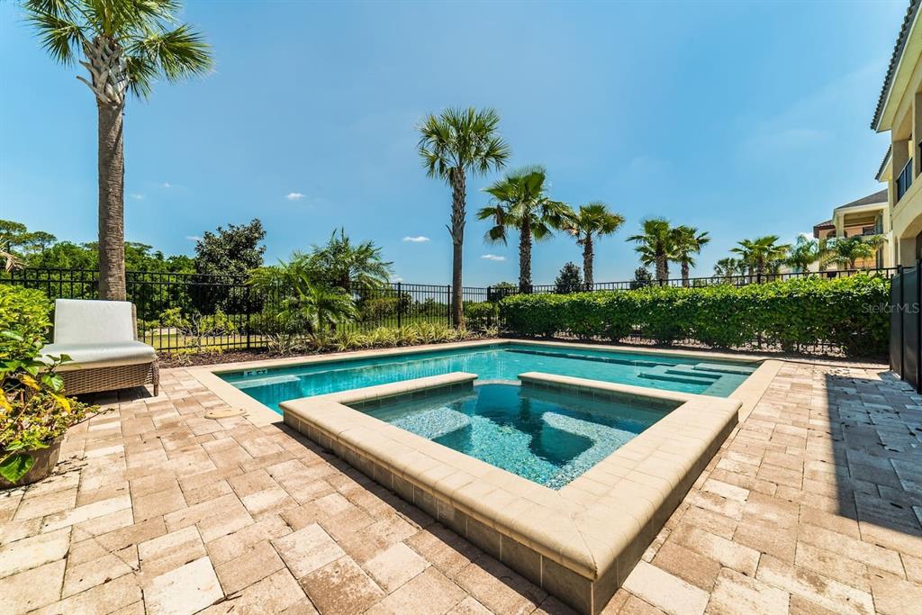 A backyard swimming pool and attached spa are surrounded by a paved patio and palm trees — 945 DESERT MOUNTAIN COURT, REUNION, FL