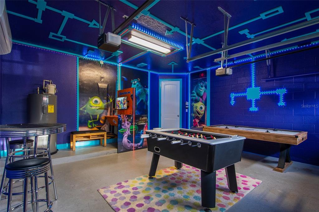 A garage converted into a game room featuring Monsters, Inc. wall murals and neon lighting — 945 DESERT MOUNTAIN COURT, REUNION, FL