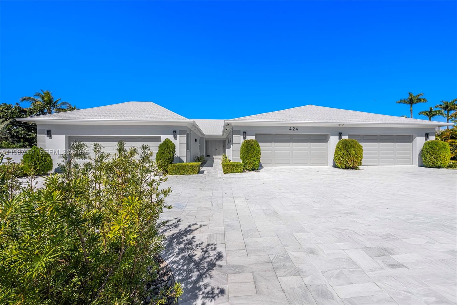 A wide exterior view shows a single-story house with a large paved driveway and garages — 424 Alamanda Dr, Hallandale Beach FL 33009, HALLANDALE BEACH, FL