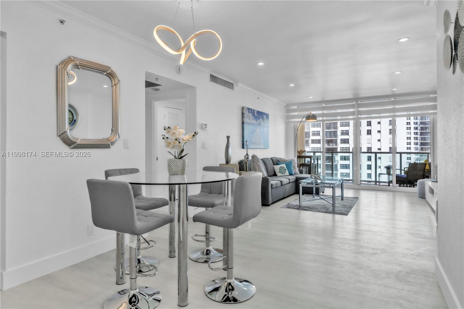 A modern open-concept living and dining area features a glass table, gray chairs, and balcony — 2501 S Ocean Dr, Hollywood FL 33019, HOLLYWOOD, FL